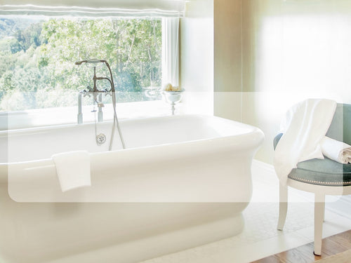 luxury bathtub with bamboo towels draped over a pretty chair