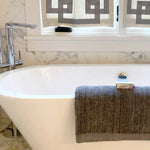 charcoal silver gray melange bamboo bath sheet and bar of soap hanging over a tub