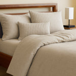 beige sand bamboo duvet cover and pillows on a wood bed frame and tan walls