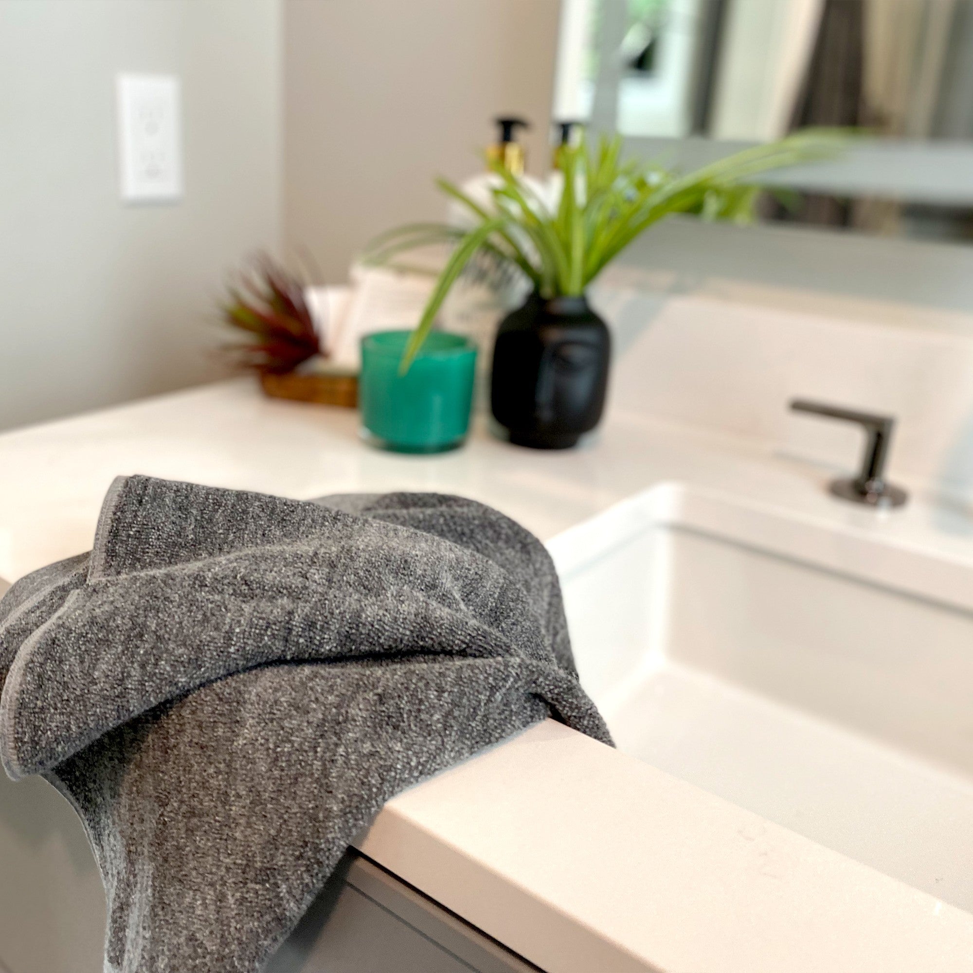 charcoal gray bamboo hand towel laying over edge of a bathroom sink 