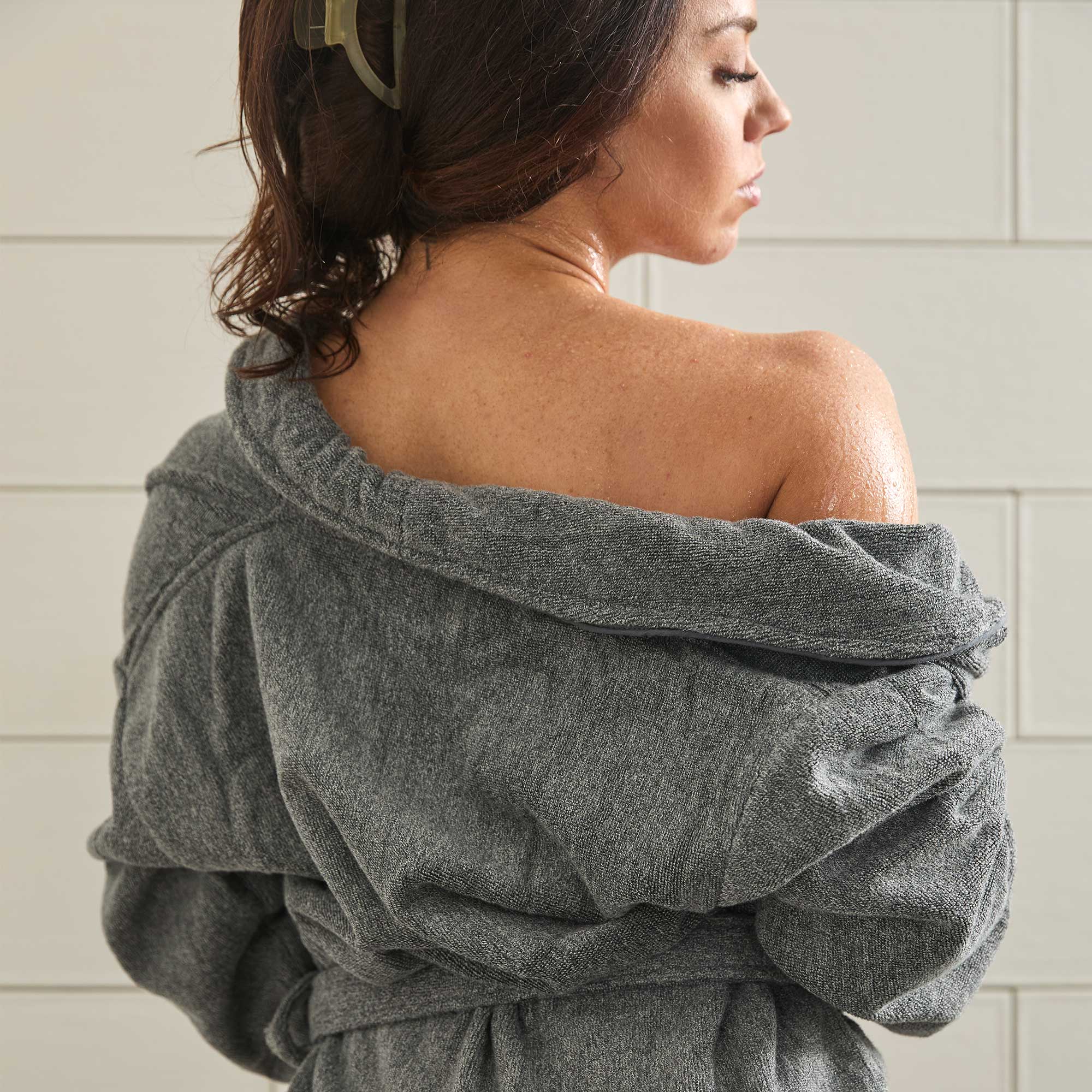 Woman wearing a gray robe in a bathroom setting