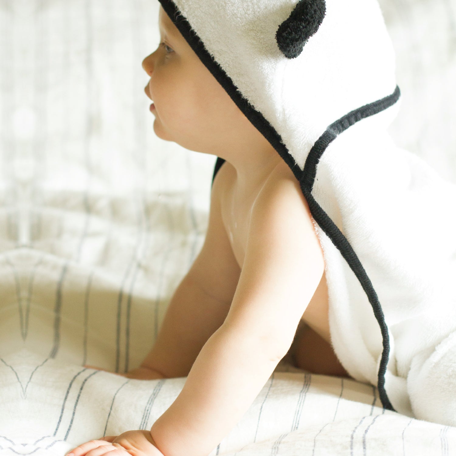 toddler boy wearing a panda hooded baby towel on a bed