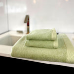 sage green bamboo 3 piece towel set stacked on bathroom sink counter