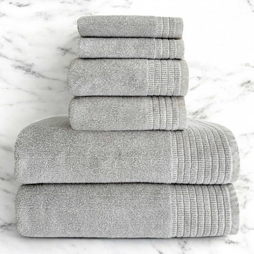 A set of folded stone gray bamboo bath towels, including bath towels, hand towels, and washcloths, displayed on a marble surface.