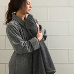 Woman wearing a gray bamboo robe against a tiled wall.