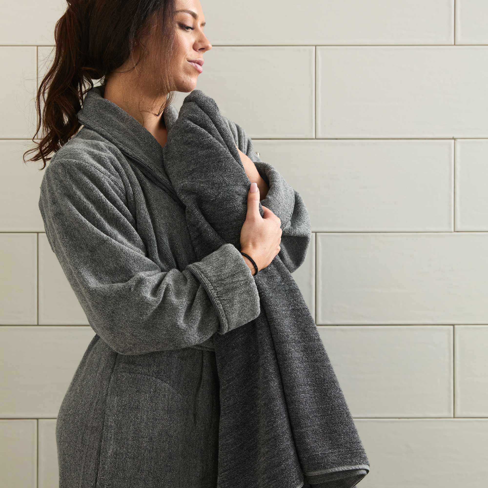 Woman wearing a gray bamboo robe against a tiled wall.