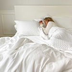 woman sleeping in bed on white snow bamboo melange quilted coverlet and standard shams