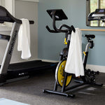 white bamboo towels hanging over stationary work out bikes in gym 