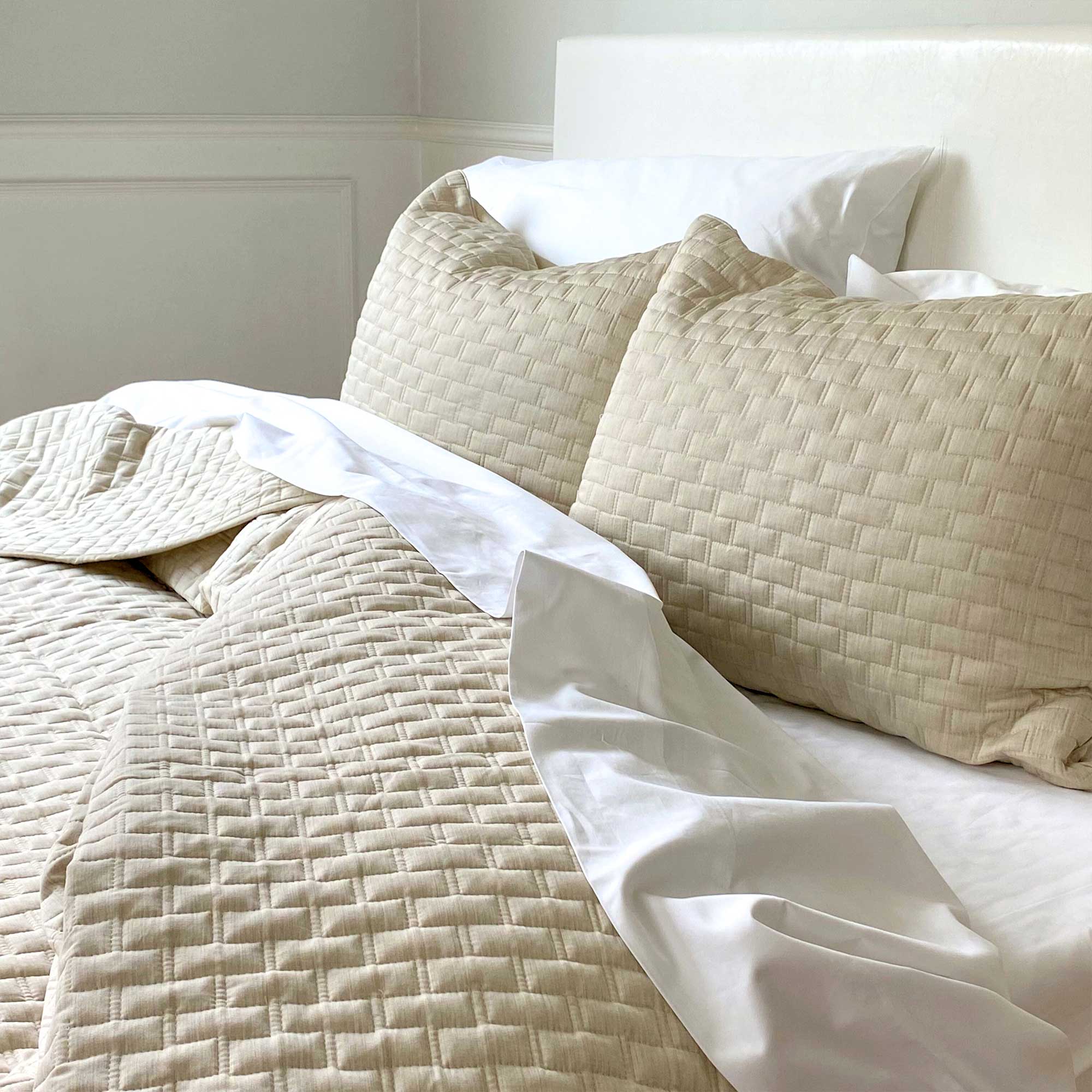cozy bed with beige sand melange bamboo quilted coverlet and white sheets on bed
