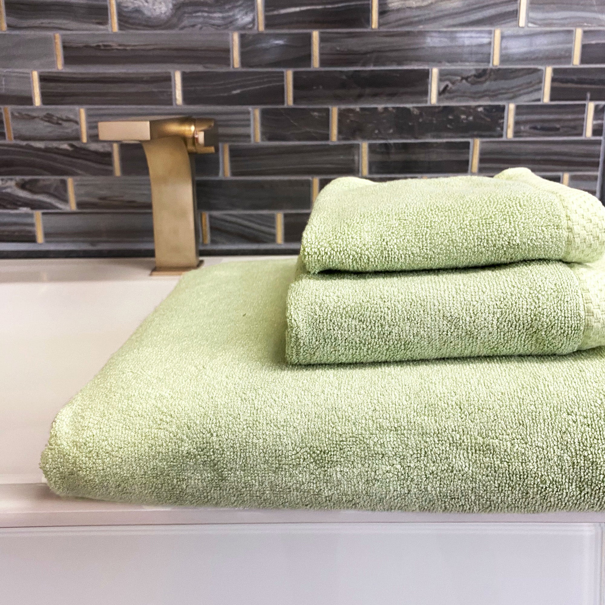3piece set of sage green stacked bamboo towels sitting on bathroom counter